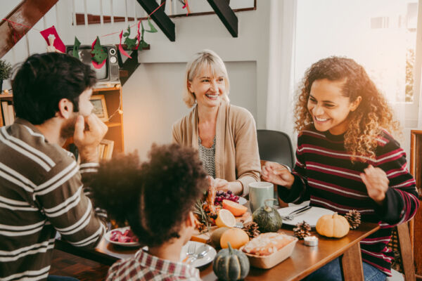 Thanksgiving Celebration Tradition Family Dinner Concept.family having holiday dinner and cutting turkey.Young black adult woman and her daughter happy.